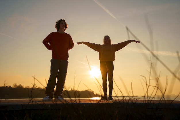 Full shot people posing at sunset