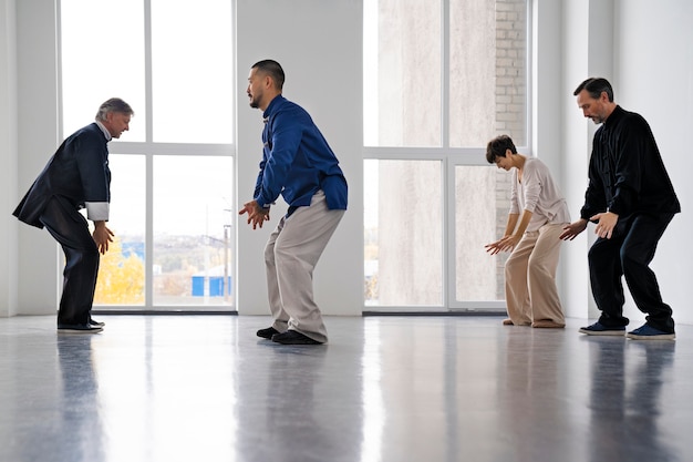 Foto gratuita persone a figura intera che praticano il tai chi al chiuso