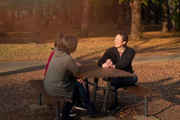 Full shot people sitting on bench outdoors