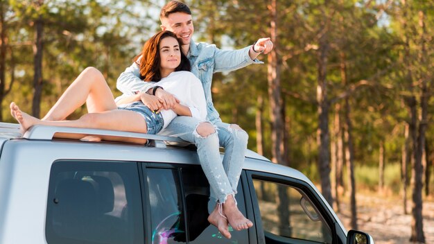 Full shot people sitting on car