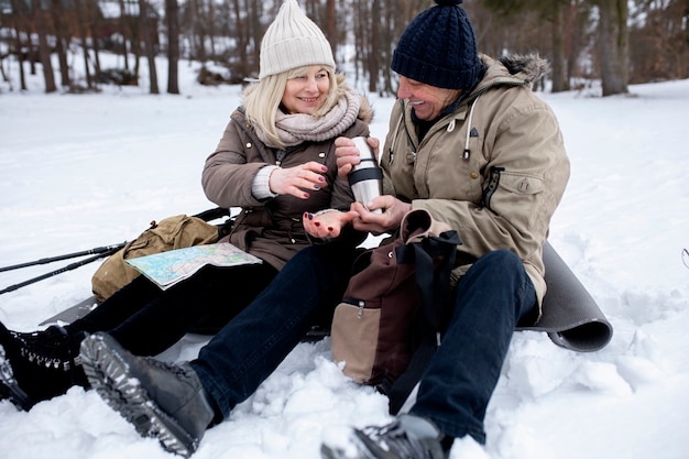 Full shot people sitting on ground winter time