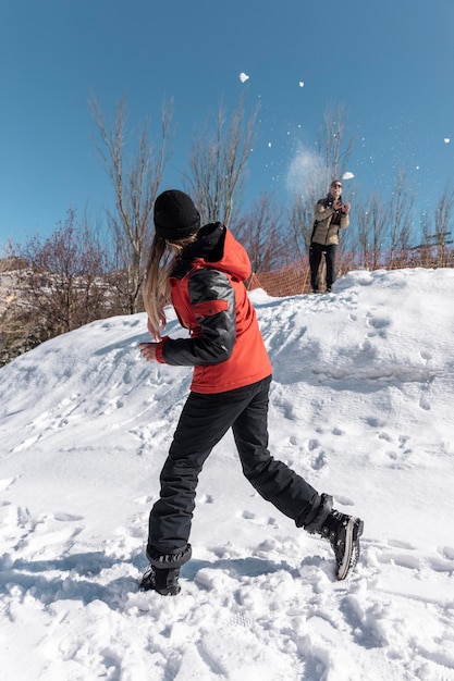 Full shot people snowball fighting