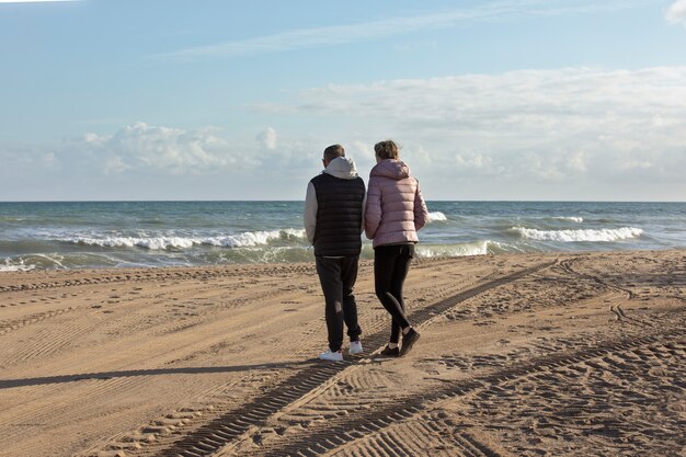 Full shot people walking at beach