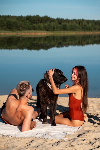 Free photo full shot people with dog on beach