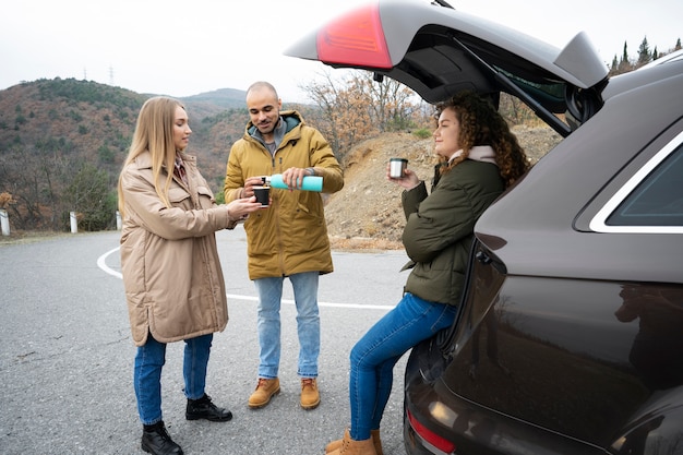 道路で飲み物を持っているフルショットの人々