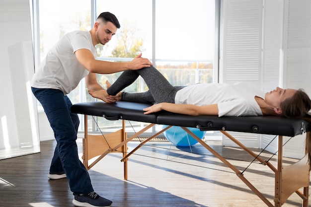 Full shot physiotherapist helping woman