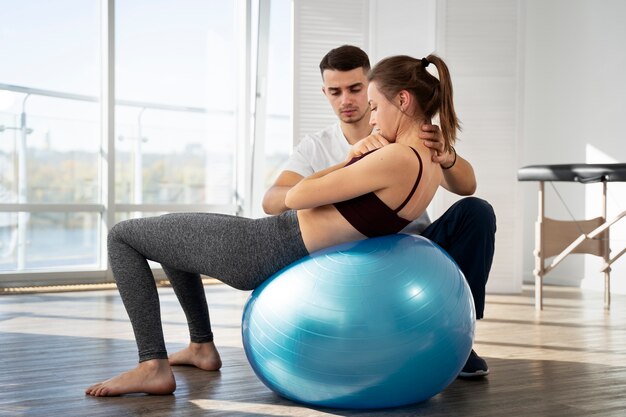 Full shot physiotherapist helping woman