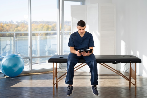 Free photo full shot physiotherapist holding tablet