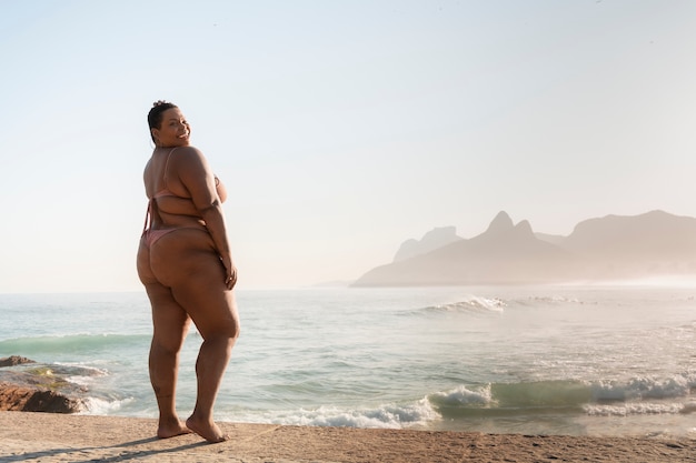 Full shot plus-size woman posing at seaside