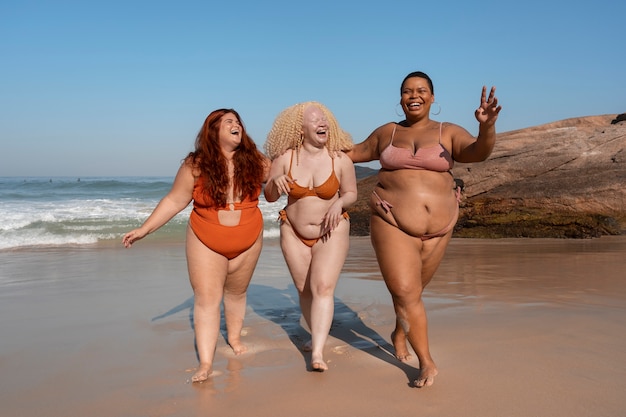 Free photo full shot plus-size women posing at seaside