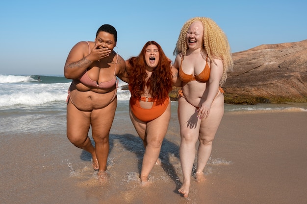 Free photo full shot plus-size women posing at seaside