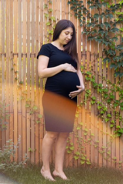 Donna incinta della foto a figura intera nella posa nera del vestito