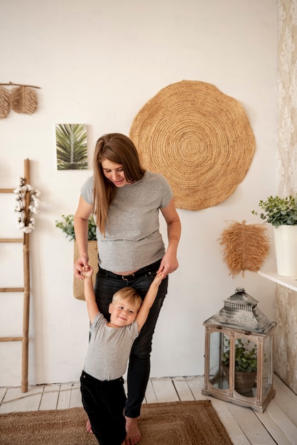 Full shot pregnant woman playing with toddler