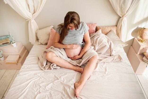 침대에 앉아 전체 샷 임신 한 여자