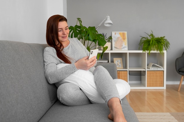 Full shot pregnant woman sitting at home