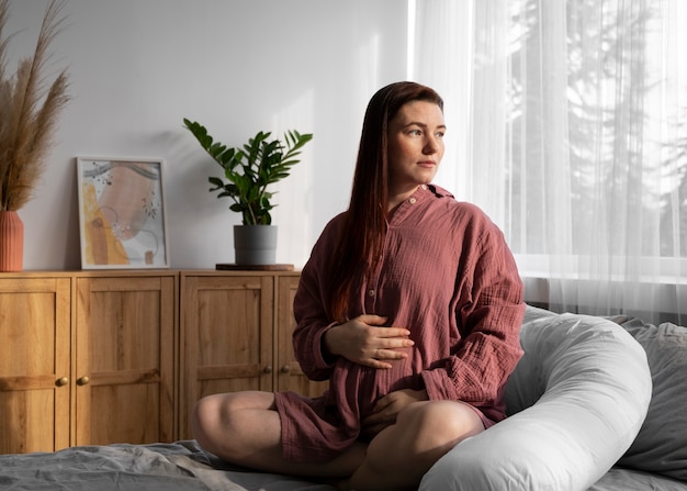 Full shot pregnant woman sitting at home