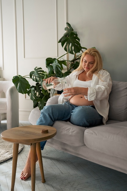 Полный кадр беременной женщины, проводящей время в помещении.