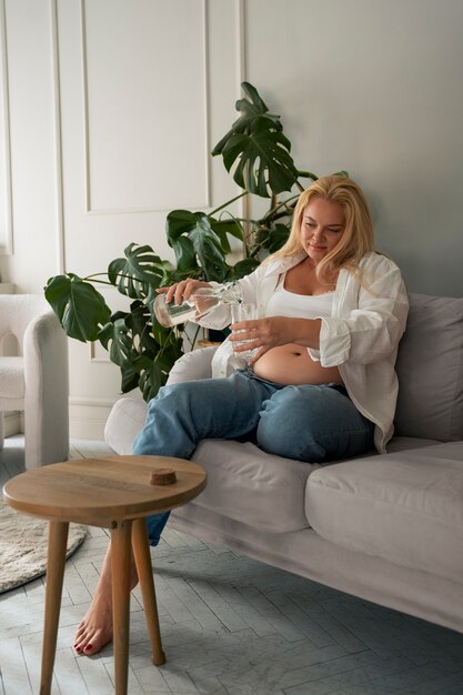 Full shot pregnant woman spending time indoors