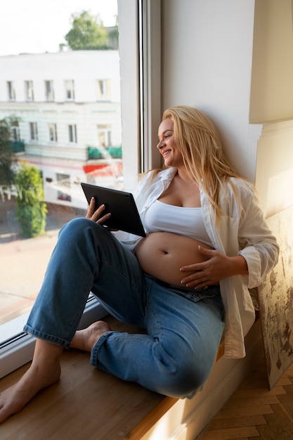 Full shot pregnant woman spending time indoors