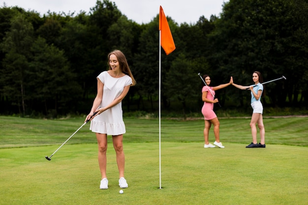 Полный выстрел симпатичных девушек, играющих в гольф