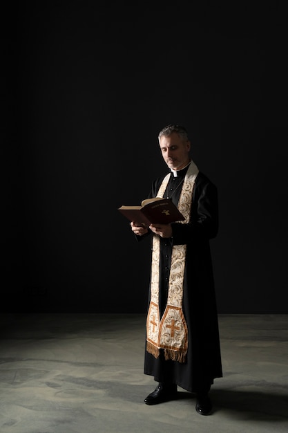 Священник в полный рост читает библию