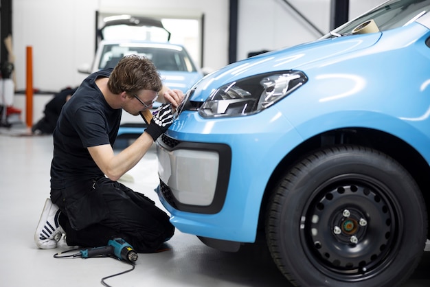 青いカバーで車を包むフルショットのプロの男