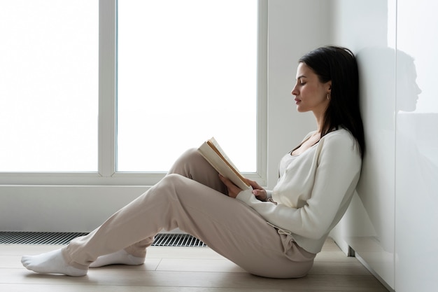 Full shot quarantined woman reading on floor