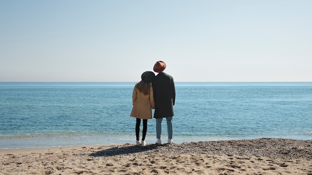Foto gratuita coppia romantica full shot in riva al mare