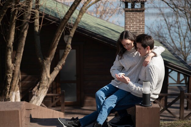 Full shot romantic couple sitting outdoors
