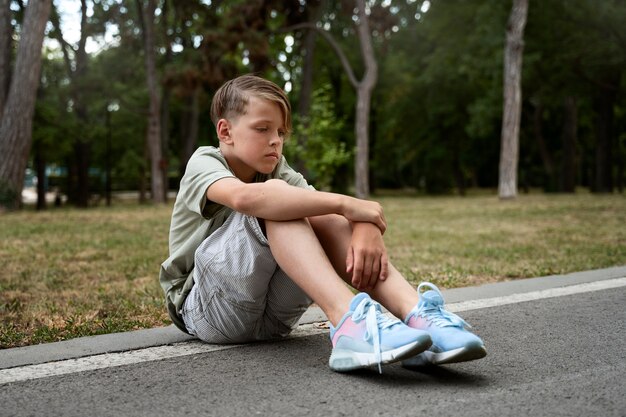 Ragazzo triste a tutto campo seduto a terra