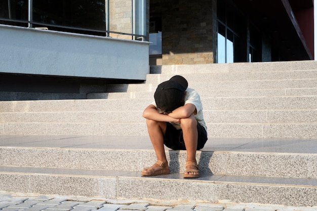 Foto gratuita ragazzo triste del colpo pieno che si siede sulle scale