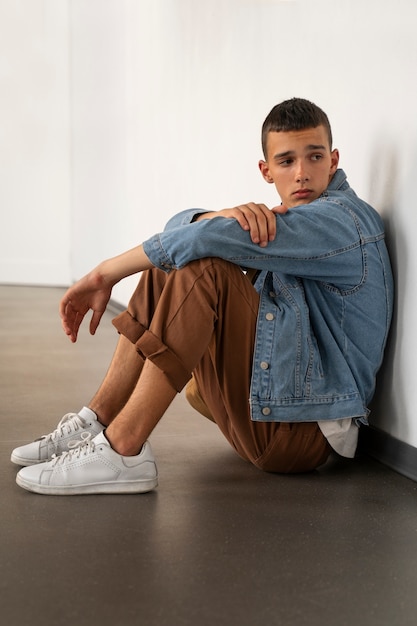 Free photo full shot sad teenager sitting on floor