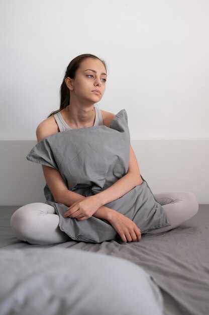 Full shot sad woman holding pillow