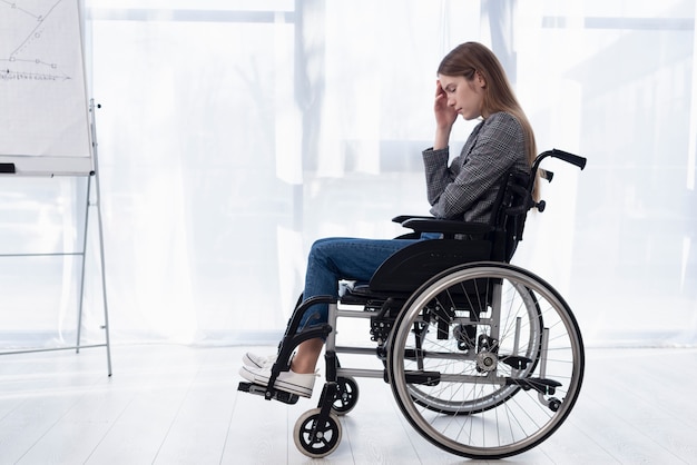Бесплатное фото Полный выстрел грустная женщина в инвалидной коляске