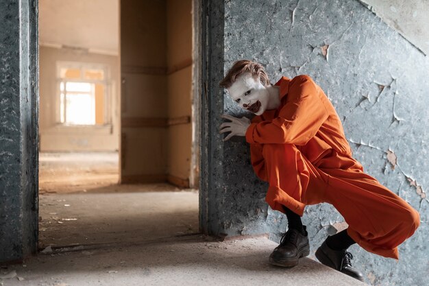 Full shot scary clown in abandoned building