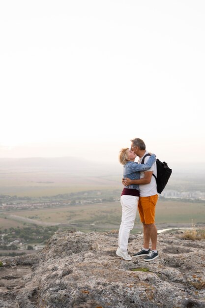 Full shot senior couple hugging on cliff