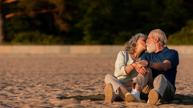 Coppia senior a tutto campo che si bacia in spiaggia?