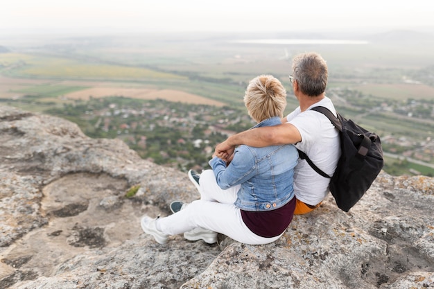 崖の上に座っているフルショットの年配のカップル