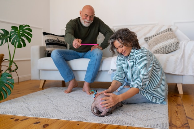 Free photo full shot senior couple with cat at home