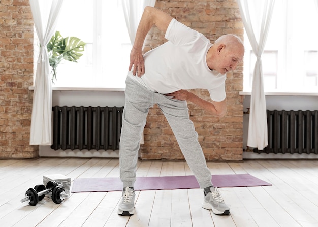 Full shot senior man exercising indoors