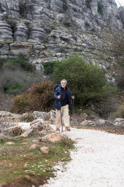 Full shot senior man hiking with equipment