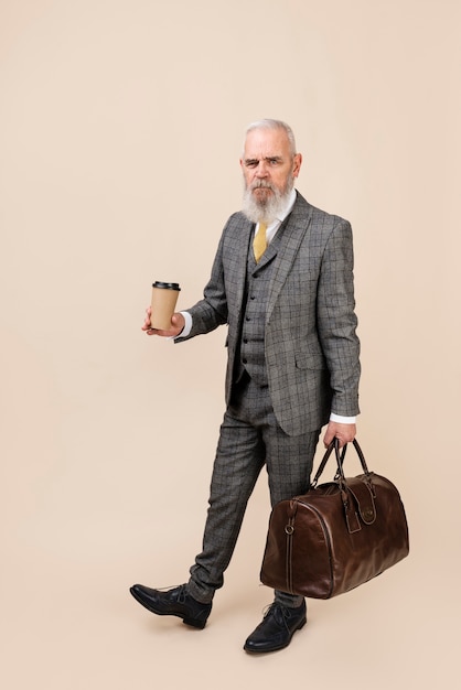 Full shot senior man holding coffee cup and baggage