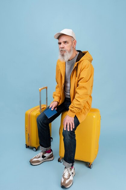 Full shot senior man sitting on baggage