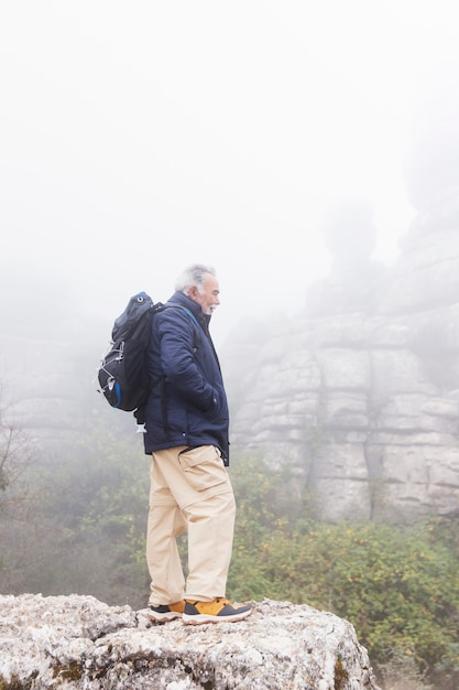 Full shot senior man standing on rock