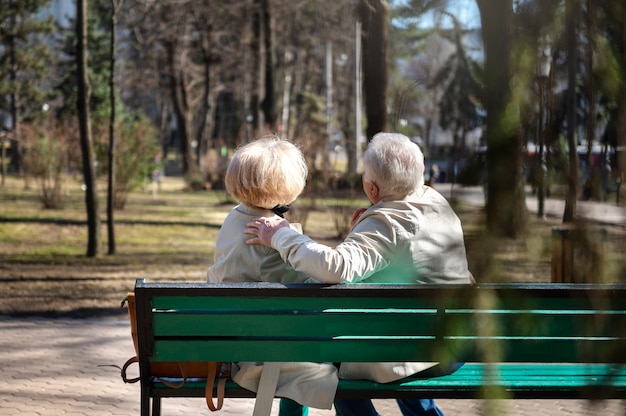 full shot senior people sitting on bench in park