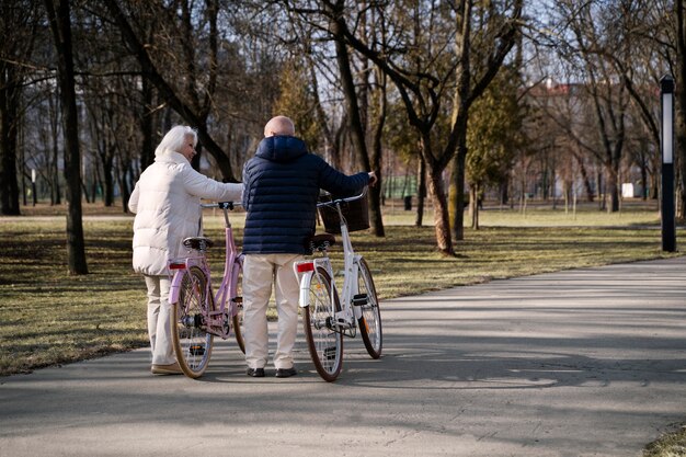 Full shot senior people with bicycles in park