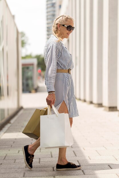 ショッピングバッグを運ぶフルショットの年配の女性