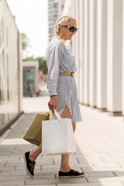 ショッピングバッグを運ぶフルショットの年配の女性