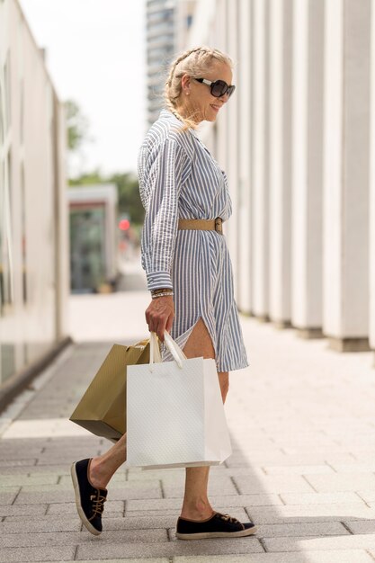 Full shot senior woman carrying shopping bags