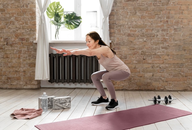 Full shot senior woman doing squats